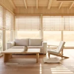 Séjour d'une maison à ossature bois resté frais en plein été, derrière des brise-soleil en bois